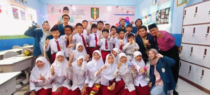 Mahasiswa Unair berfoto dengan Peserta Usai Penyuluhan dan Sosialisasi Anti-Konten Negatif di Ruang Kelas 5 SDM Limas