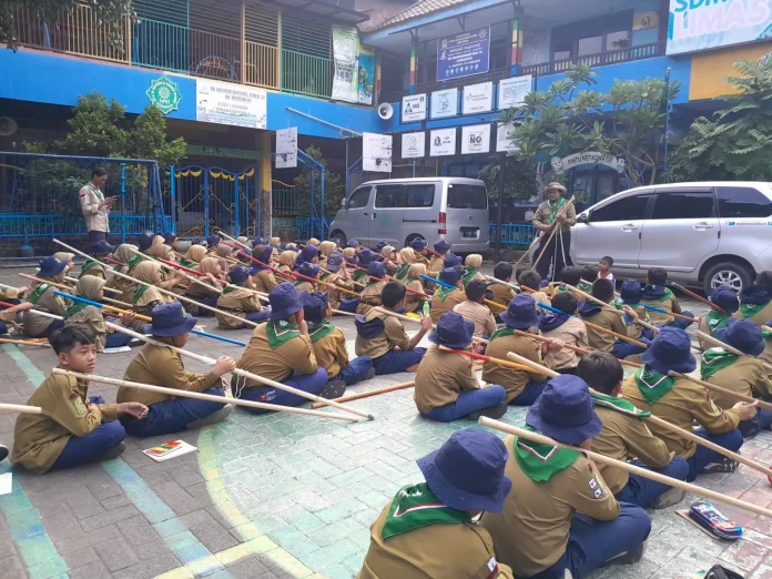 Suasana Kepanduan Hizbul Wathan (HW) SD Muhammadiyah 15 Surabaya (SDM Limas) Bikin Menara Kaki Tiga bersama Ramanda Dody Poernomo SPSI dan Yogi Prasetyo SPd di halaman Sekolah (Ali/PWMU.CO)